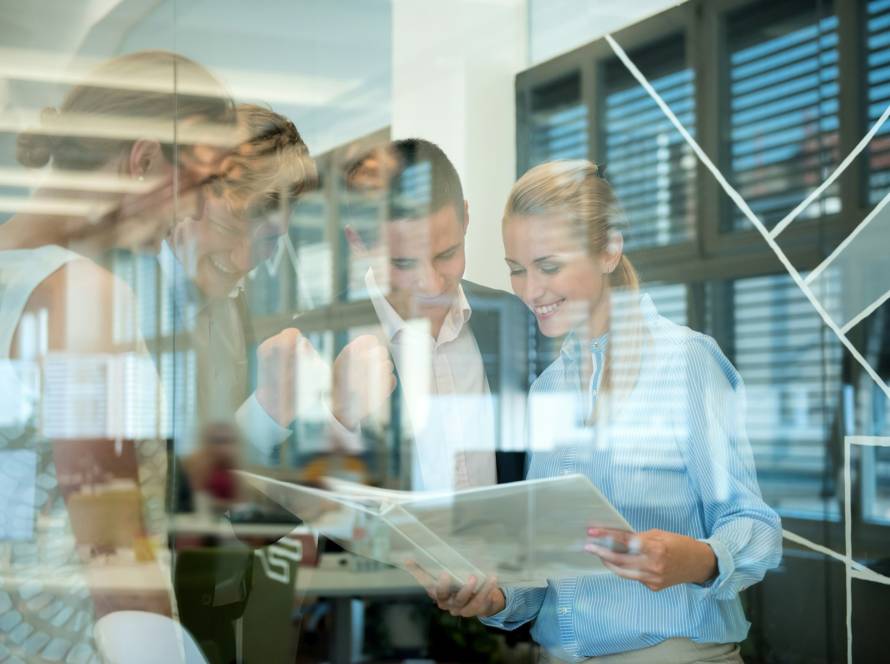 Successful business team behind glass wall in office looking at folder